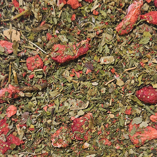 A close up of the "Satisfaction" blend - a bright green bed of dried strawberry and spearmint leaves interspersed with vibrant red freeze dried strawberry pieces