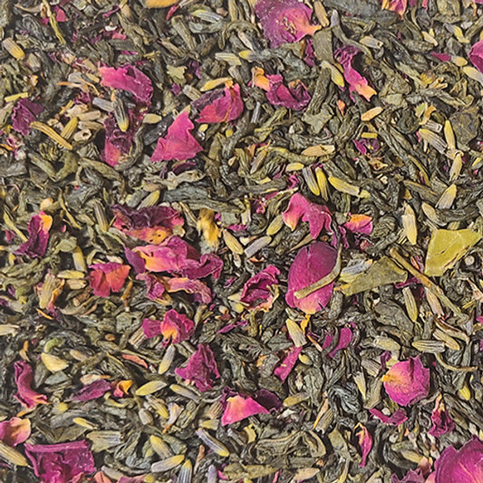 A close up of the Unrelenting Love blend - vibrant green tea leaves interspersed with blue-green lavender petals and bright violet rose petals